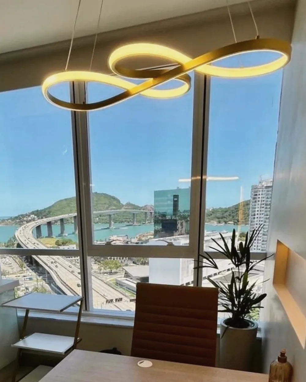 Sala de atendimento com janela ampla, luminária dourada e vista para a Terceira Ponte